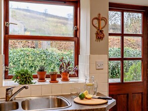 A kitchen with a sink, a window with a view of greenery, and a heart-shaped decoration on the wall. - 2 Bed in Berwick -upon- Tweed (oc-cn181) (Spittal)
