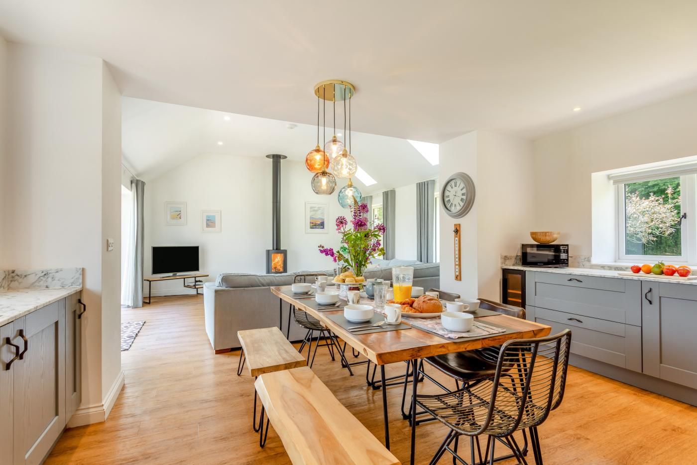 A modern kitchen with a dining area, a built-in stove, and a large window.
