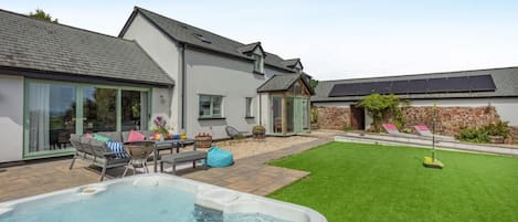 A modern house with a swimming pool, a patio with outdoor furniture, and a well-maintained lawn.