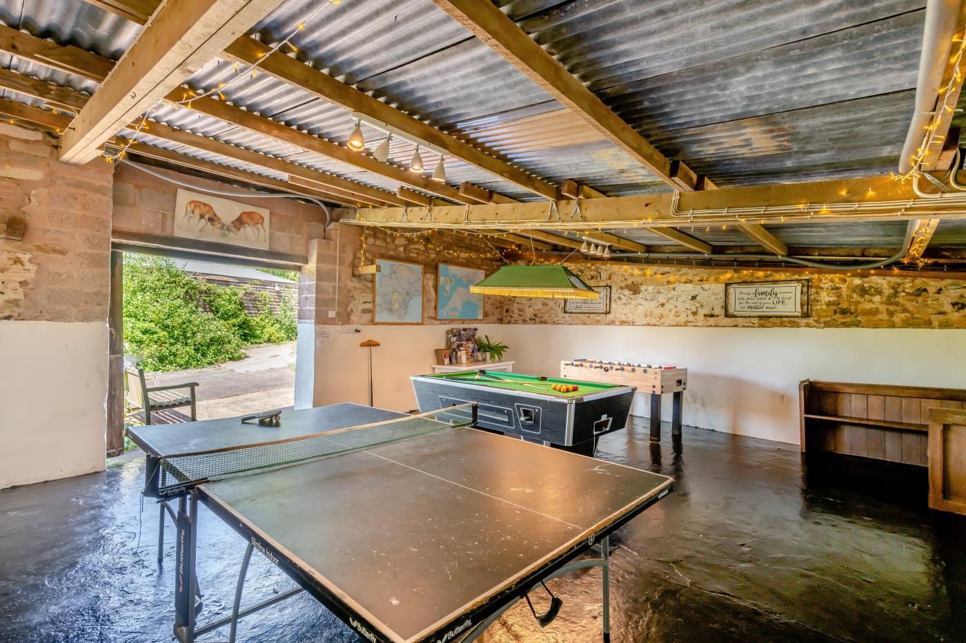 An indoor recreational area with a ping pong table, foosball table, and a billiards table.