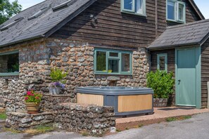 A stone house with a hot tub, a wooden door, and a window.