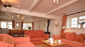 Ein gemütliches Wohnzimmer mit Kamin, Essbereich und einer Küche im Hintergrund.