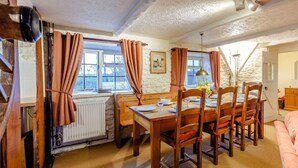 Ein Essbereich mit Holztisch und -stühlen, einem Heizkörper und einem Fenster mit Vorhängen.