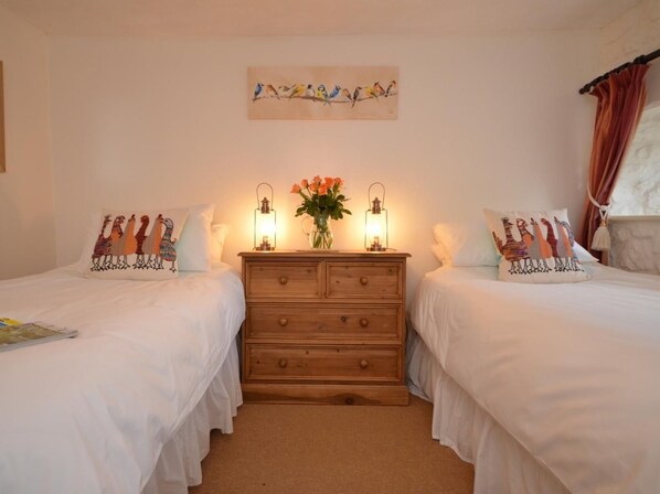 A bedroom with two beds, a wooden dresser, and wall art.