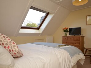 A bedroom with a sloped ceiling, a skylight, a bed, a dresser, a television, and a vase with flowers. - 4 Bed in Honiton (oc-41045) (Sheldon)