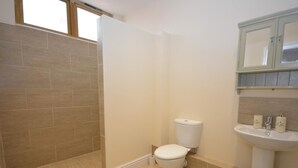 A bathroom with a toilet, a sink, and a shower area. - 1 Bed in Axminster (oc-36491) (Dalwood)