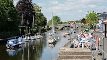 A canal with boats, a bridge, and people sitting on a dock.