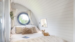 A bedroom with a bed, a window, a mirror, and a rabbit.