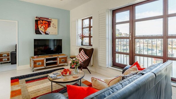 Ein Wohnzimmer mit Sofa, Fernseher und einem großen Fenster mit Blick auf die Stadt.