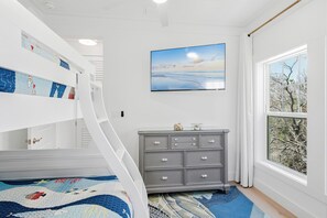 A bedroom with a bunk bed, a dresser, a painting, and a window with a view. - Serenity Seas - All New Luxury Home Across from Beach w/ Heated Pool, Mini Golf (Indian Rocks Beach)