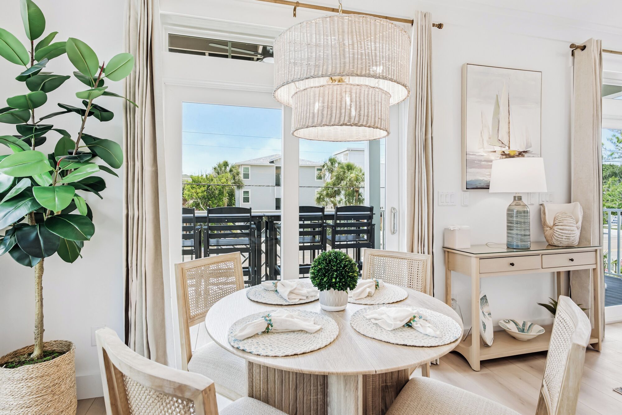 A dining area with a round table, chairs, a hanging light fixture, and a view of the outside.