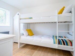 A bunk bed with white bedding and a colorful striped pillow. - 4 Bed in Bude (oc-66706) (Bude)