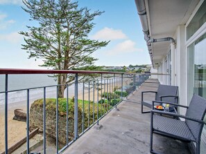 A balcony with a view of the beach, a tree, and a table with chairs. - 1 Bed in Saundersfoot (oc-fb019) (Saundersfoot)