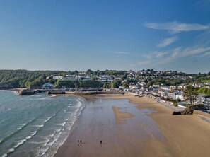 A coastal town with a sandy beach, a pier, and residential buildings. - 1 Bed in Saundersfoot (oc-fb019) (Saundersfoot)