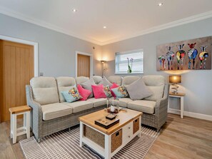 A living room with a sofa, cushions, a coffee table, a lamp, a painting, and a window with blinds. - 3 Bed in Cottingham (oc-94350) (Raywell)