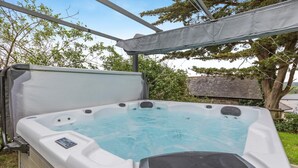 A hot tub with a control panel, surrounded by a covered area with trees and a wooden fence in the background. - 1 Bed in Bideford (oc-folly) (Buckland Brewer)