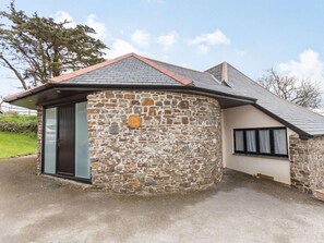 A stone house with a sloped roof, a glass door, and a small window. - 2 Bed in Bideford (oc-60765) (Buckland Brewer)