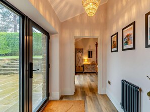 A hallway with a glass door leading outside, a wooden floor, a chandelier, and framed pictures on the wall. - 8 Bed in Settle (oc-94323) (Settle)