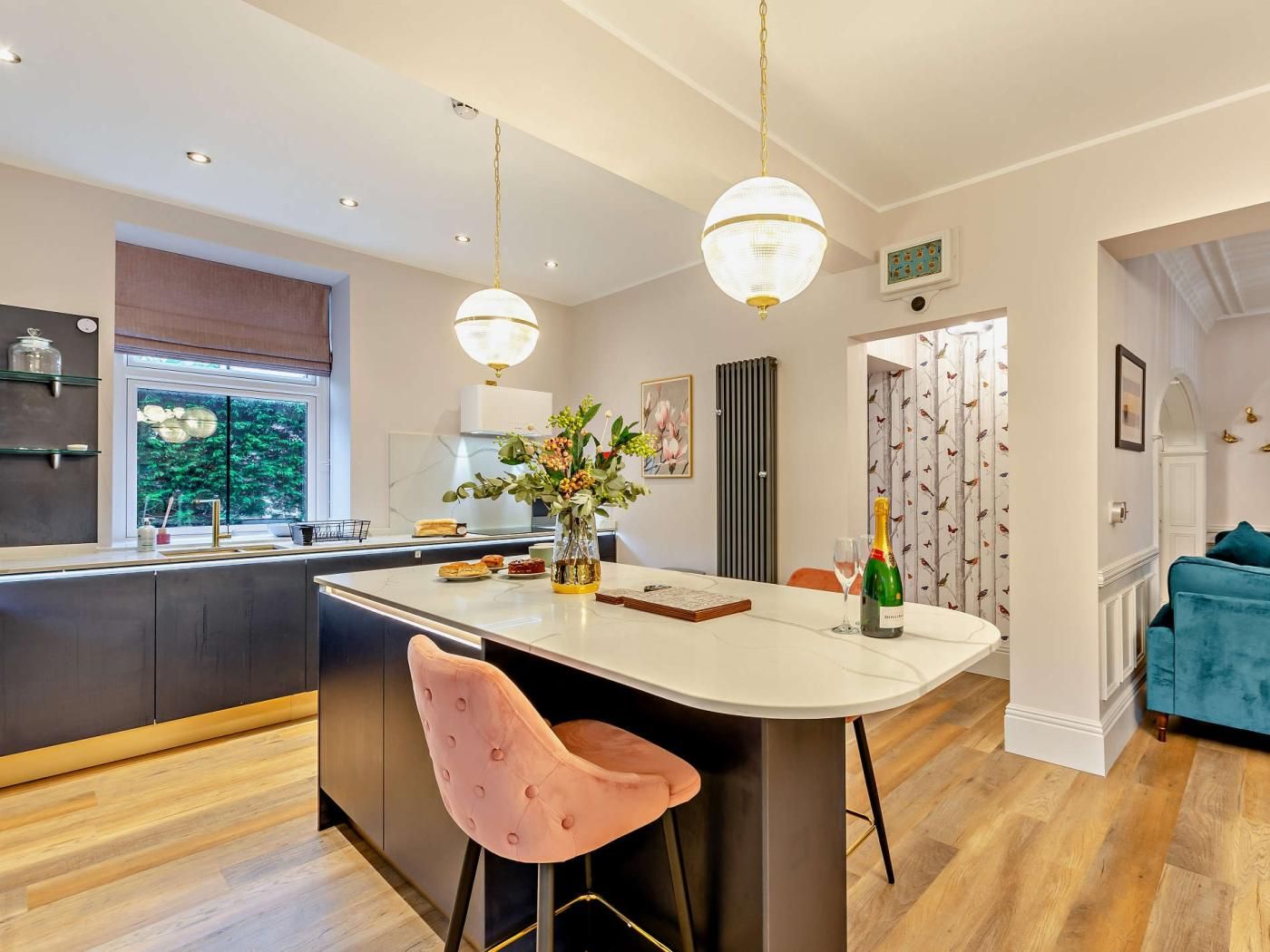 Een moderne keuken met een centraal eiland, hanglampen en uitzicht op de omgeving.