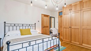 A bedroom with a bed, wooden wardrobe, and a mirror. - 2 Bed in Ulverston (oc-91730) (Blawith)