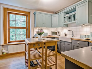 A kitchen with a window, wooden table, wine rack, and light blue cabinets. - 2 Bed in Ulverston (oc-91730) (Blawith)