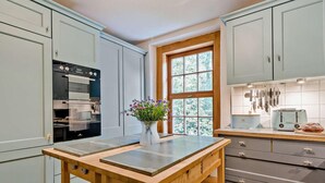 A kitchen with light blue cabinets, a wooden table, a window with a view, and a toaster on the counter. - 2 Bed in Ulverston (oc-91730) (Blawith)