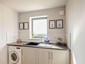 A compact kitchen with a built-in washing machine, a sink, and a window with a view. - 2 Bed in Skipton (oc-94056) (Tosside)