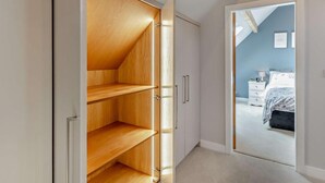 Ein Schlafzimmer mit einem Bett, einem Nachttisch und einem Holzschrank mit vielen Regalen.