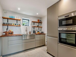 A modern kitchen with stainless steel appliances, wooden shelves, and a window. - 3 Bed in Sheffield (oc-94342) (Thurlstone)