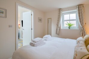 A bedroom with a bed, a window with curtains, a door, and a small potted plant on the windowsill. - 1 Bed in Lytham St. Annes (oc-86044) (Saint Anne's on the Sea)