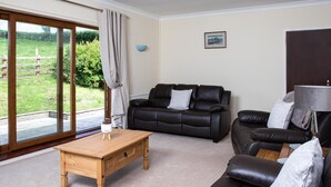 A living room with a sofa, a coffee table, and a lamp. - 3 Bed in Brecon (oc-bn419) (Llandeilo'r-Fan)