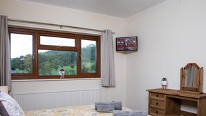A bedroom with a bed, a dresser, a television, and a window with a view of trees. - 3 Bed in Brecon (oc-bn419) (Llandeilo'r-Fan)