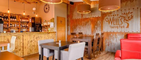 A restaurant interior with wooden beams, a bar area with bottles, and a red seating area.