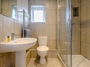Un baño con lavamanos, inodoro y cabina de ducha de vidrio.