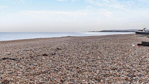 Ein Kiesstrand mit einem Boot und einer Pier im Hintergrund.