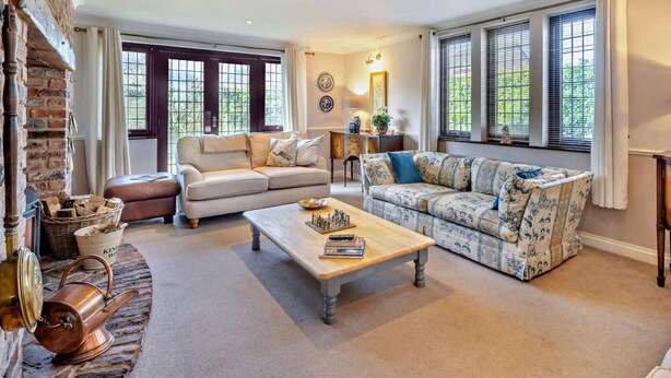 A living room with a fireplace, two sofas, a coffee table, and a brick wall. - 4 Bed in Carlisle (oc-94398) (Crosby-on-Eden)