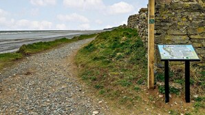A coastal path with a stone wall and a signboard. - 4 Bed in Millom (oc-94429) (Silecroft)
