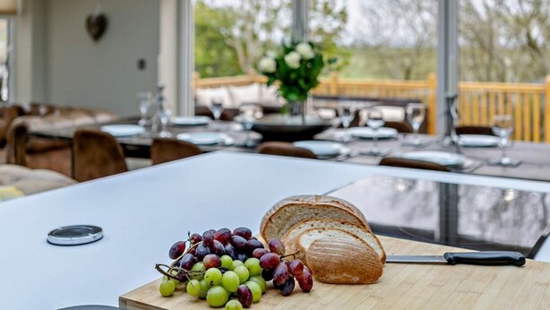 A dining table with a loaf of bread and grapes, a knife, and a glass. - 4 Bed in Millom (oc-94429) (Silecroft)