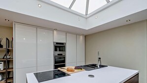 A modern kitchen with a central island, built-in ovens, and a skylight. - 4 Bed in Millom (oc-94429) (Silecroft)