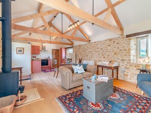 A spacious living area with a stone wall, a fireplace, and a cozy seating arrangement. - 1 Bed in Stoke Abbott (oc-94405) (Stoke Abbott)
