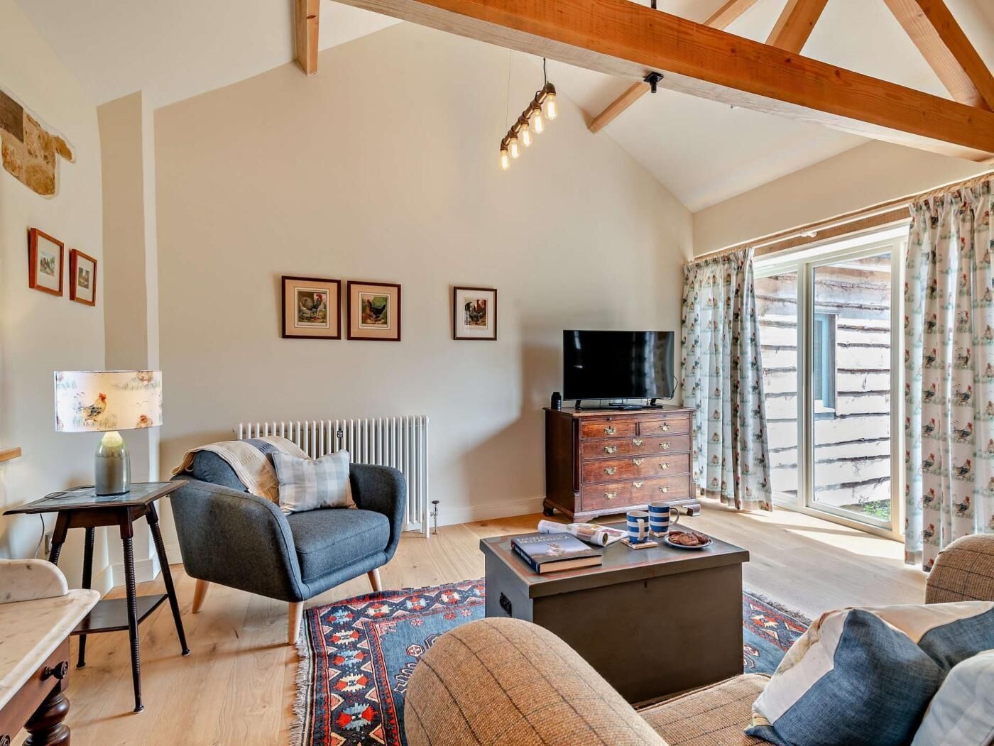 A spacious living room with a high ceiling, a fireplace, a television, and a large window with curtains.