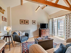 A spacious living room with a high ceiling, a fireplace, a television, and a large window with curtains. - 1 Bed in Stoke Abbott (oc-94405) (Stoke Abbott)