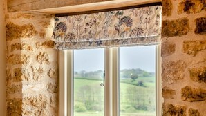 Una ventana con un adornado floral y vista a un paisaje verde.