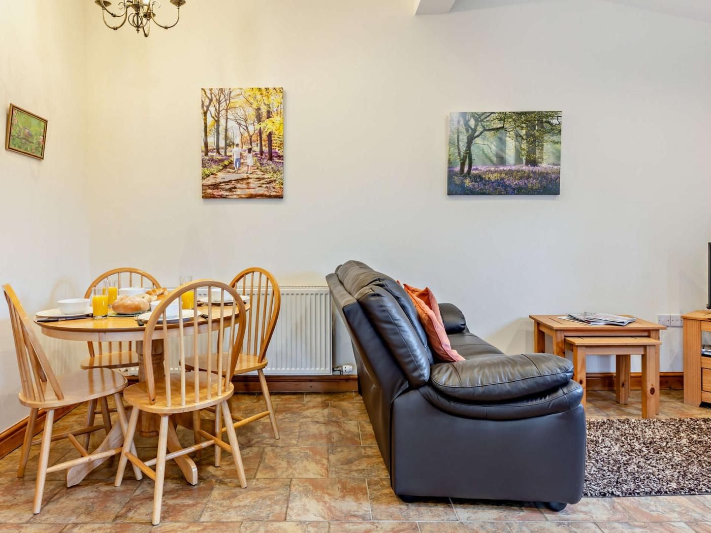Ein Wohnzimmer mit Esstisch, Stühlen, einer Couch und Kunstwerken an den Wänden.