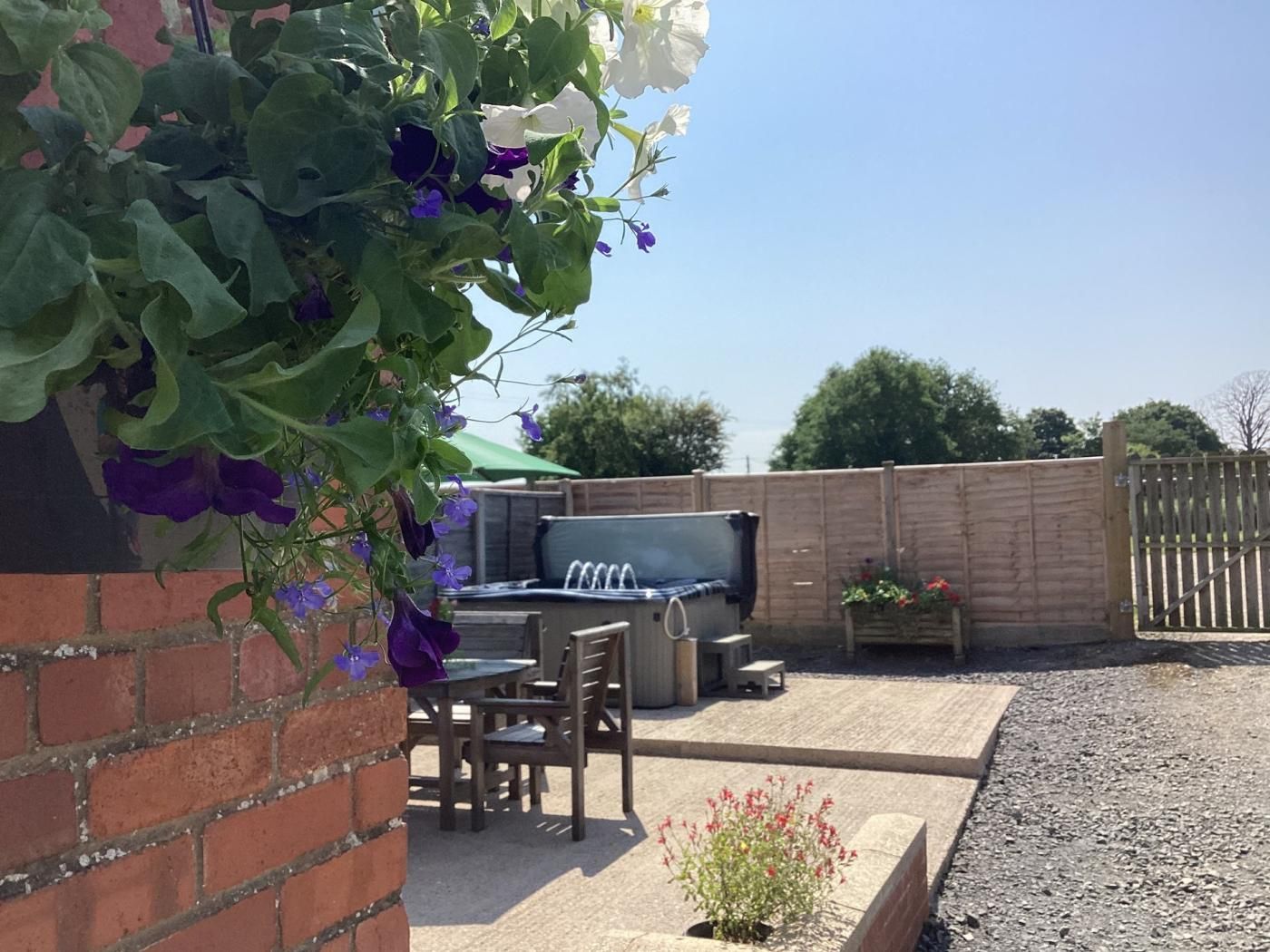 Een terras met een barbecue, buitenzitgelegenheid en een bakstenen muur begroeid met klimplanten.