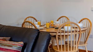 A dining area with a round wooden table, four chairs, and breakfast items including croissants and orange juice. - 3 Bed in Ellesmere (oc-94419) (Dudleston)