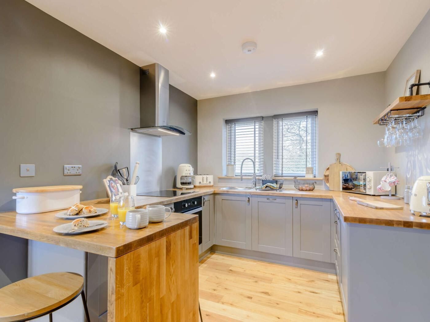 A modern kitchen with a central island, a built-in oven, and a window with blinds.