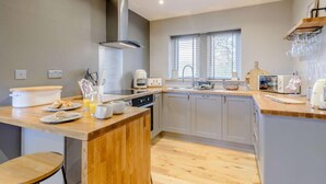 A modern kitchen with a central island, a built-in oven, and a window with blinds. - 1 Bed in Colne (oc-86513) (Trawden)