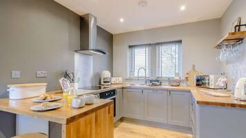 A modern kitchen with a central island, a built-in oven, and a window with blinds.