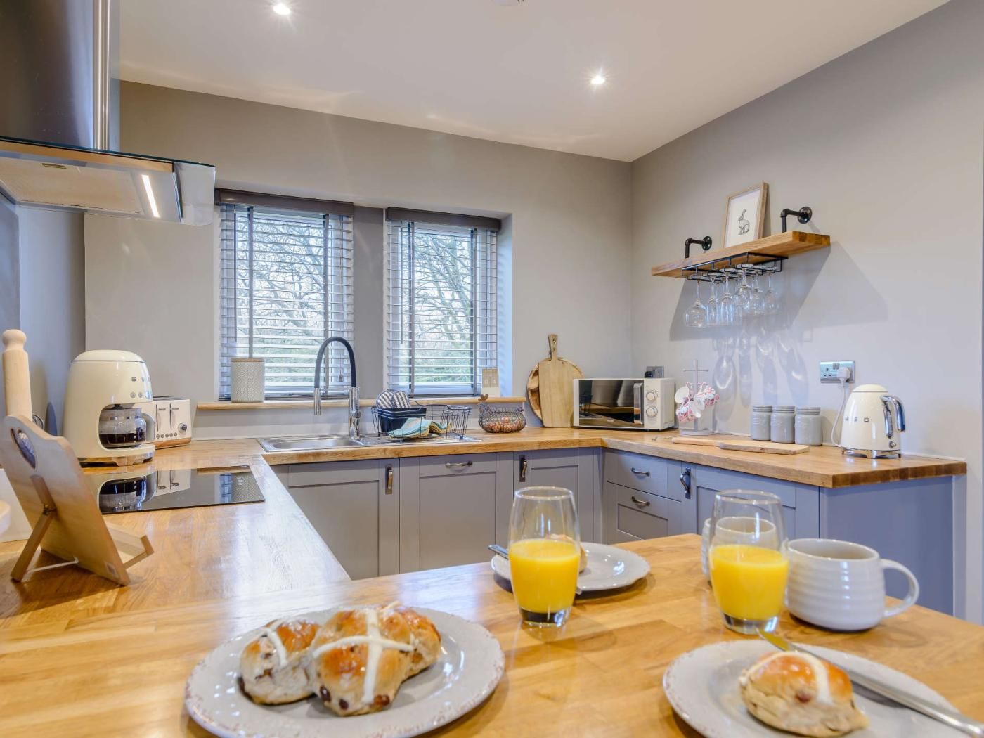 Una cucina moderna con piano di lavoro in legno, lavello e zona pranzo con piatti di cibo e bicchieri di succo d'arancia.